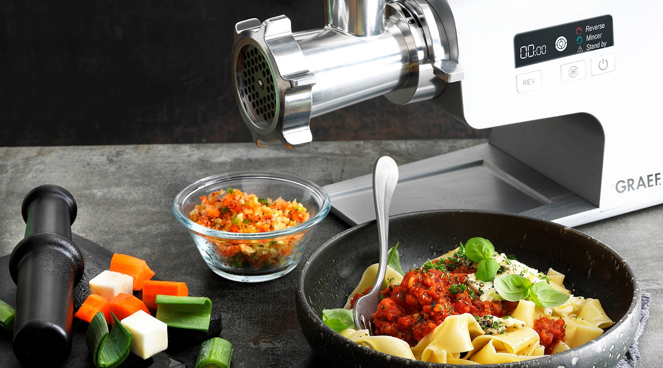 Tritacarne con verdure e pasta. Concetto di cucina e preparazione del cibo.