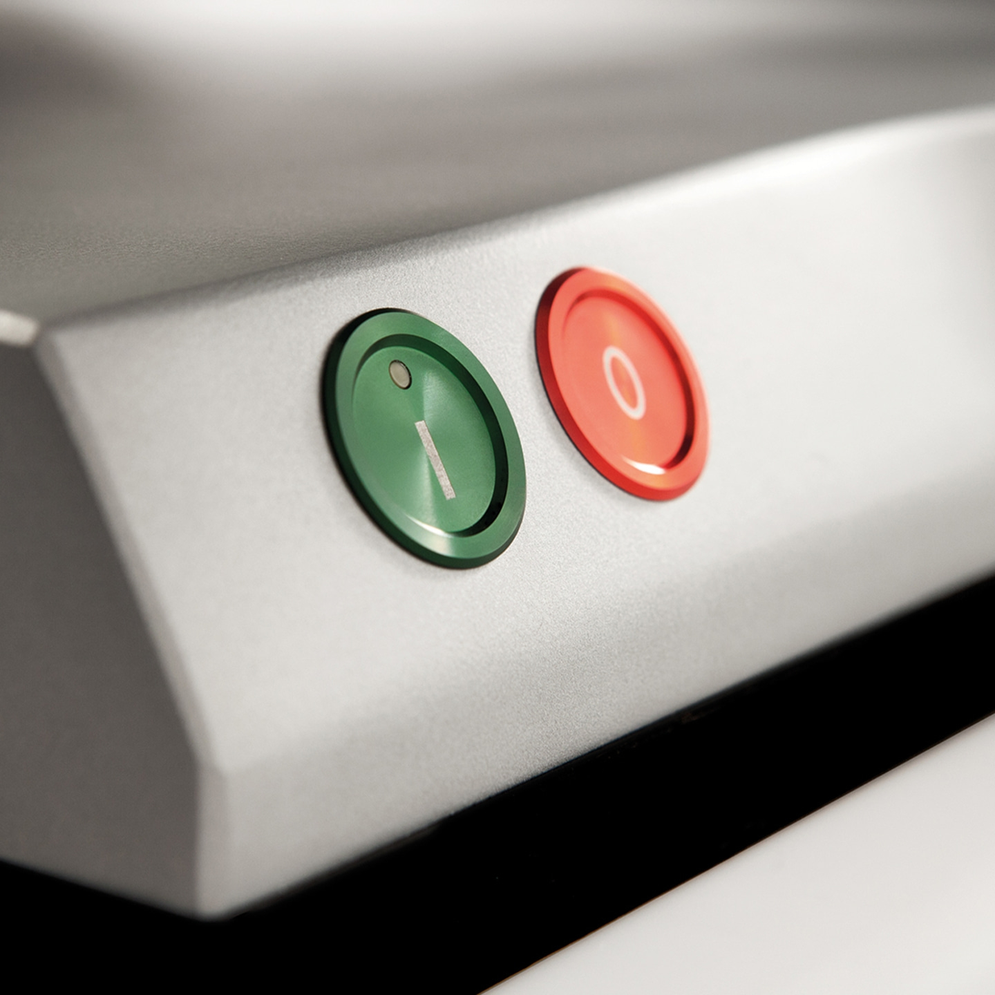 Boutons verts et rouges sur une surface argentée avec les chiffres 1 et 0 affichés.