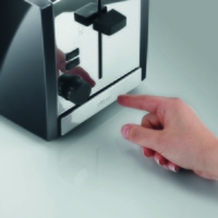 Gros plan d'un grille-pain avec une main appuyant sur le bouton.