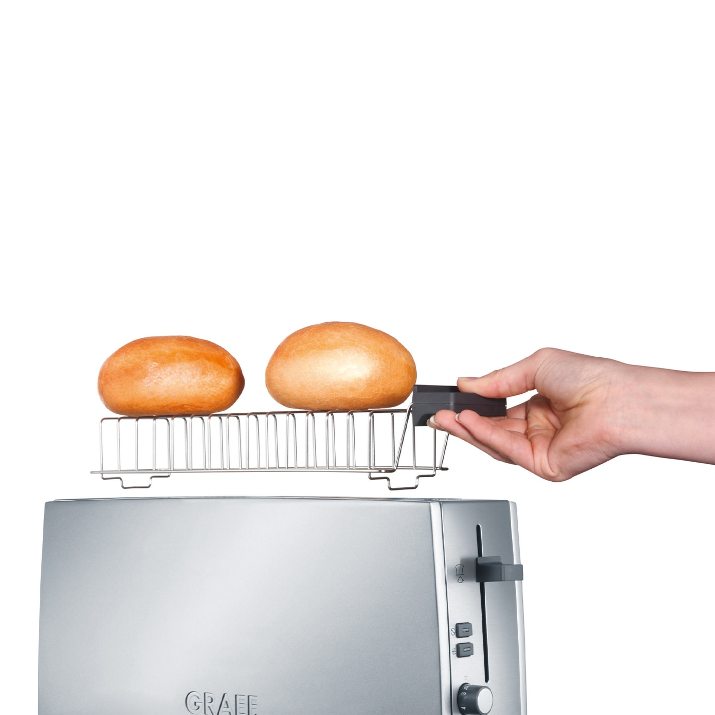Grille-pain avec accessoire à pain et deux petits pains tenus par une main.