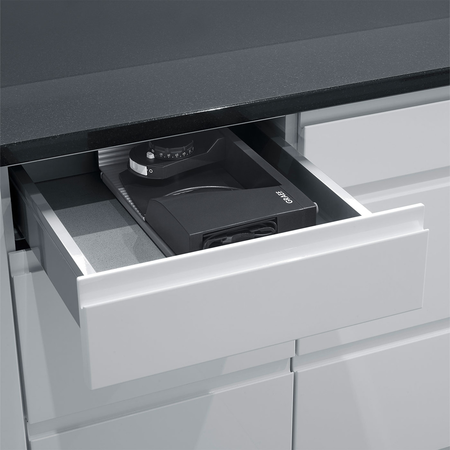 Drawer with coffee grinder, black countertop, kitchen cabinet, Graef logo visible.