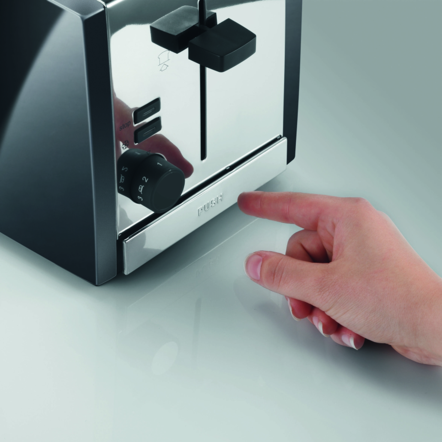 Gros plan d'un grille-pain avec une main appuyant sur le bouton.